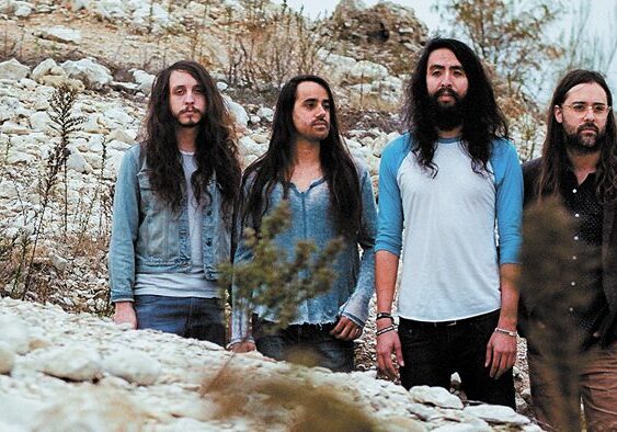 Four men standing on rocky terrain outdoors.