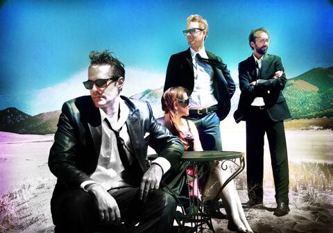 Four people in suits posing outdoors.