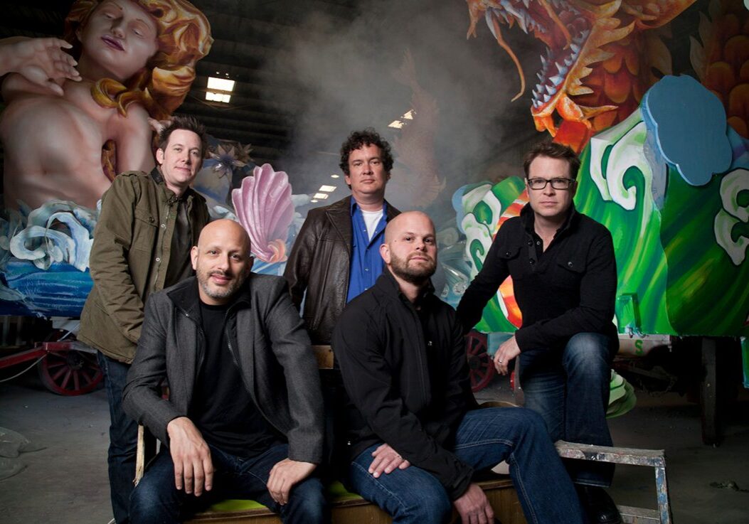 Five men posing in front of parade float.