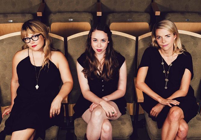 Three women sitting in theater seats.