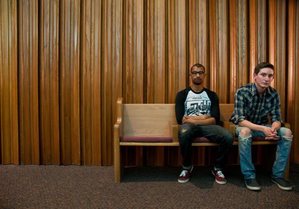 Two men sitting on a wooden bench.