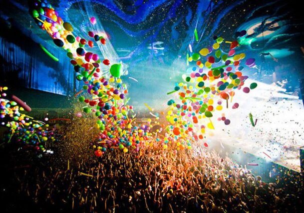 Concert crowd with balloons and confetti celebration.