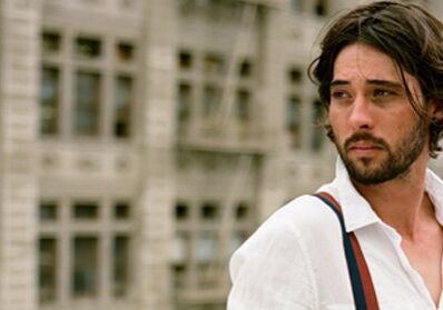 Man in white shirt with suspenders outdoors.