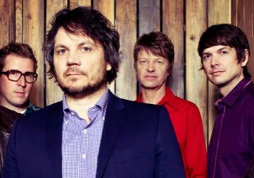 Band members posing in front of wood wall.