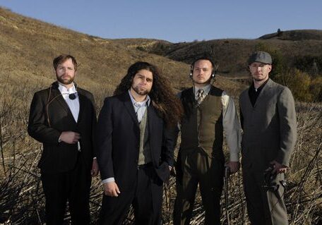 Four men in suits standing outdoors.