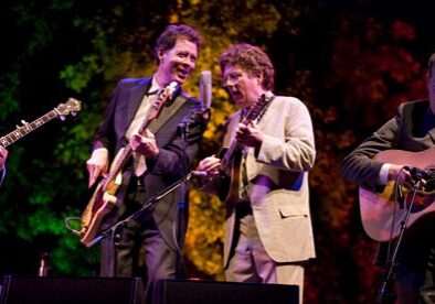 Four musicians performing on stage with instruments.