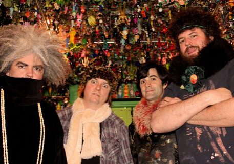 Four people posing in colorful, eclectic setting.