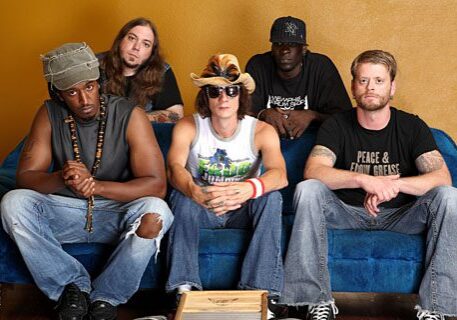 Five men sitting on a blue couch.