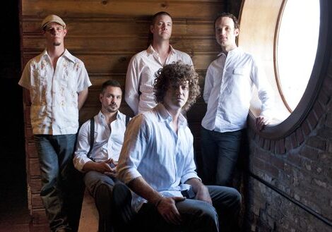Five men posing near a round window.