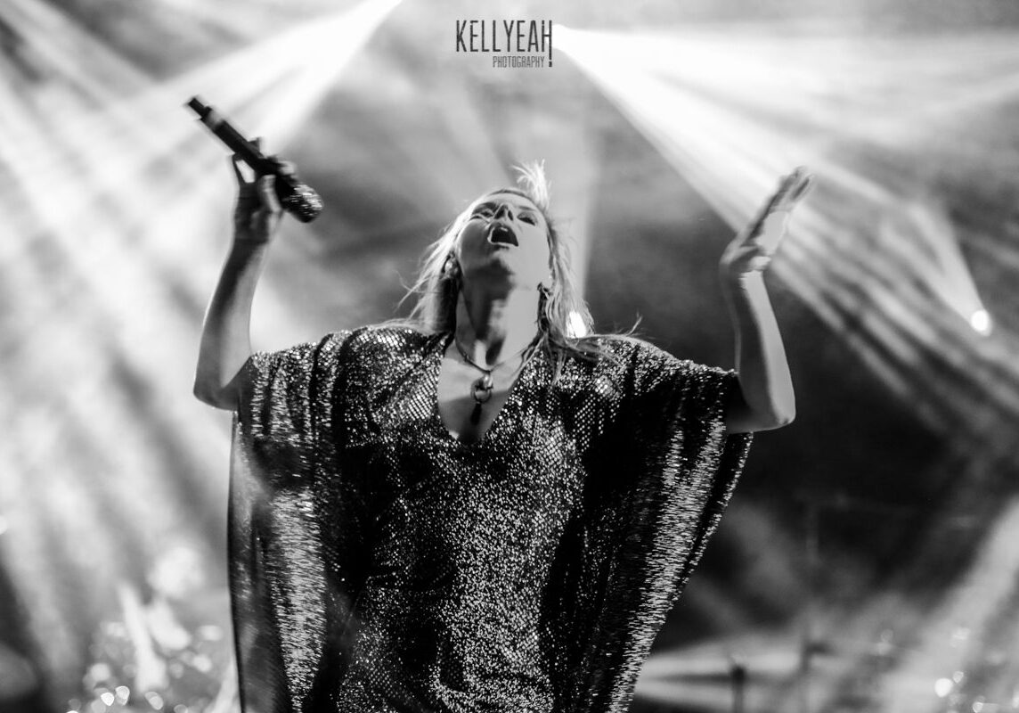 Singer performing passionately on stage with spotlight.