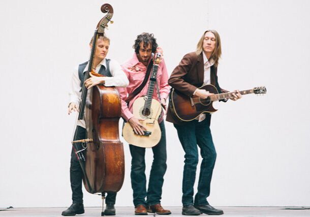 Three musicians playing instruments on stage.