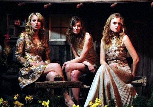 Three women seated in rustic outdoor setting.