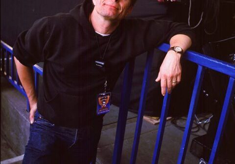Man leaning on railing at concert stage.