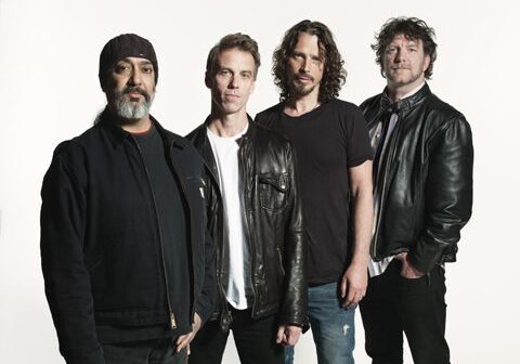 Four men in leather jackets posing together.