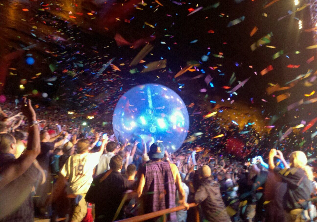 Concert crowd with confetti and giant ball.