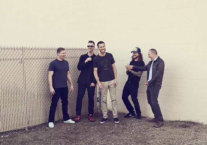 Group of five men standing and laughing.