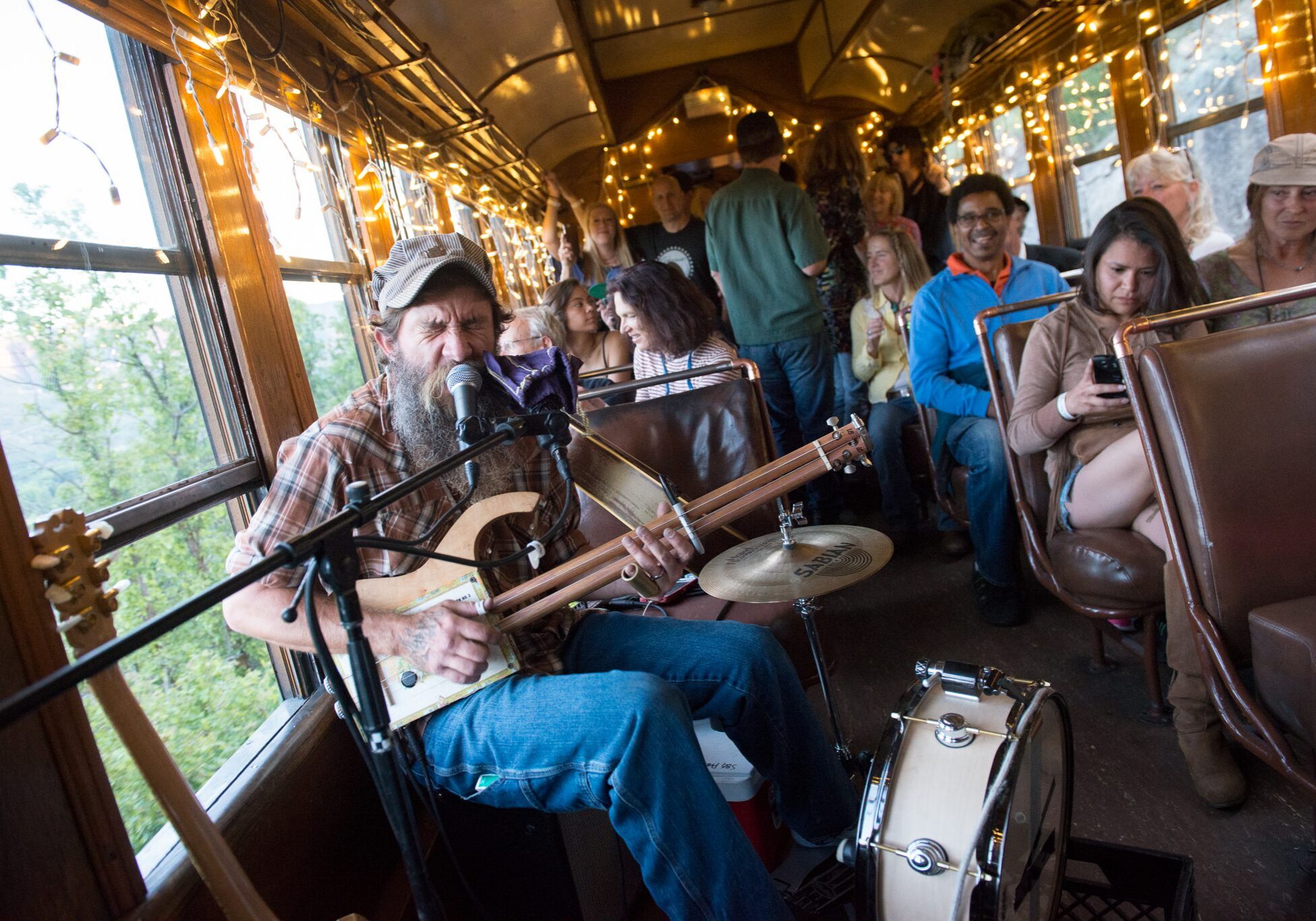 Musician performing on train with seated audience.