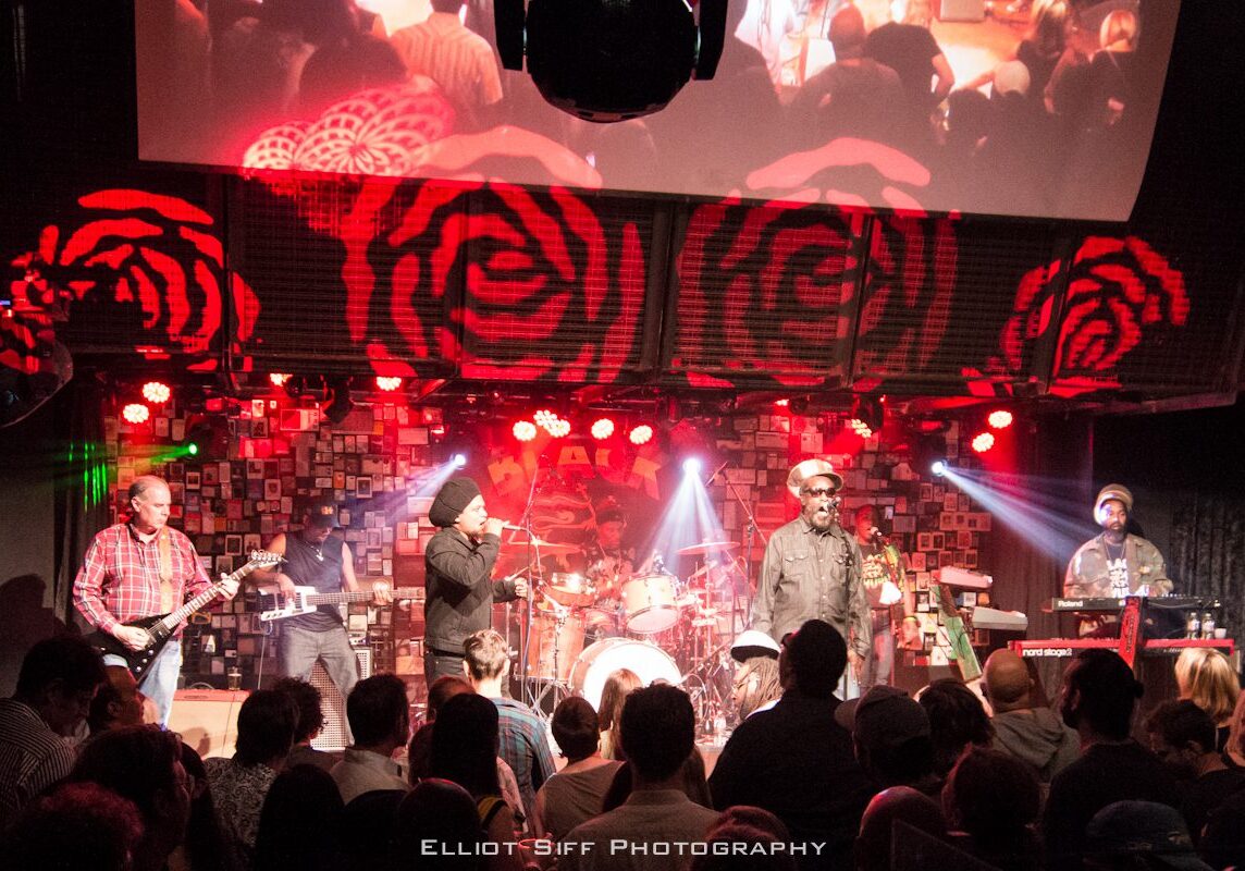 Band performing on stage with vibrant lights.
