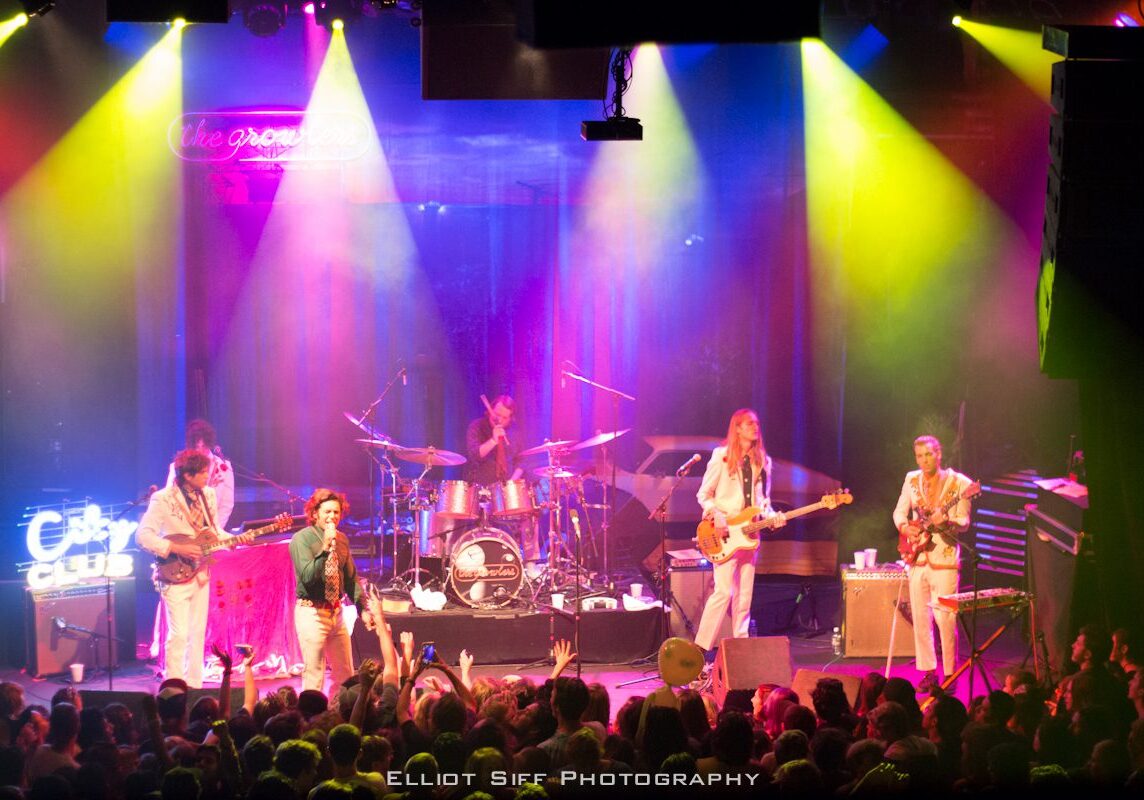 Band performing on stage with colorful lights.