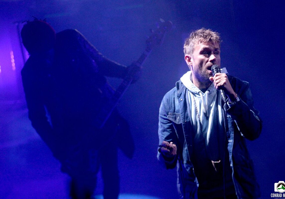 Singer performing live on stage with guitarist.