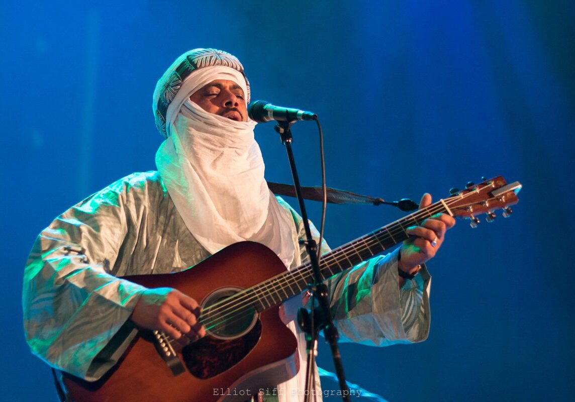 Musician in traditional attire playing guitar.