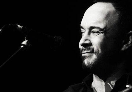 Man singing into a microphone, black and white.