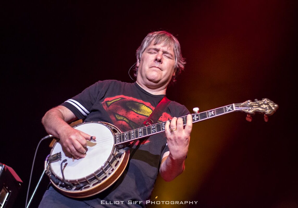 Musician playing banjo on stage.