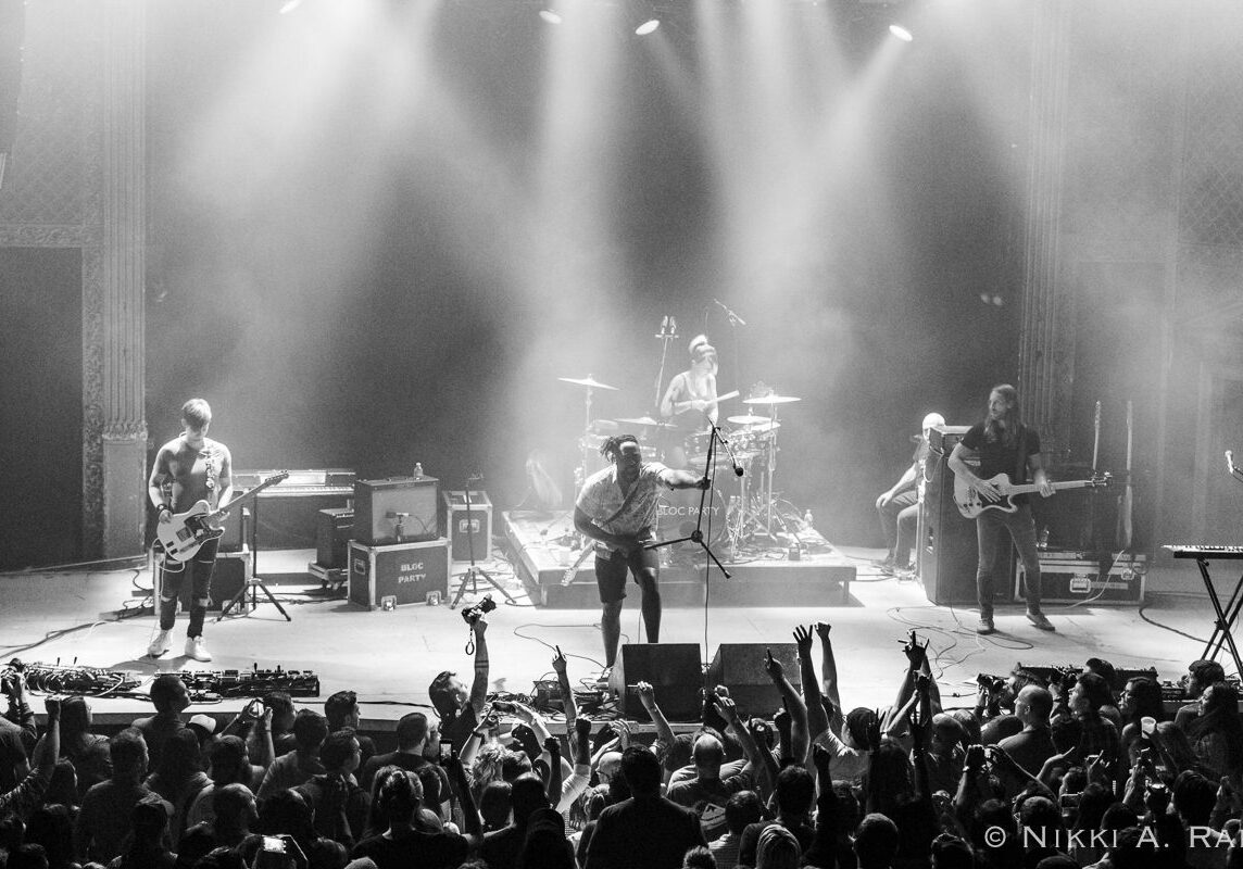 Band performing on stage with audience cheering.