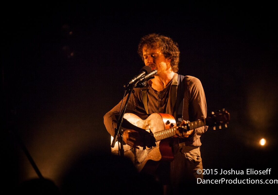 Musician performing on stage with guitar.