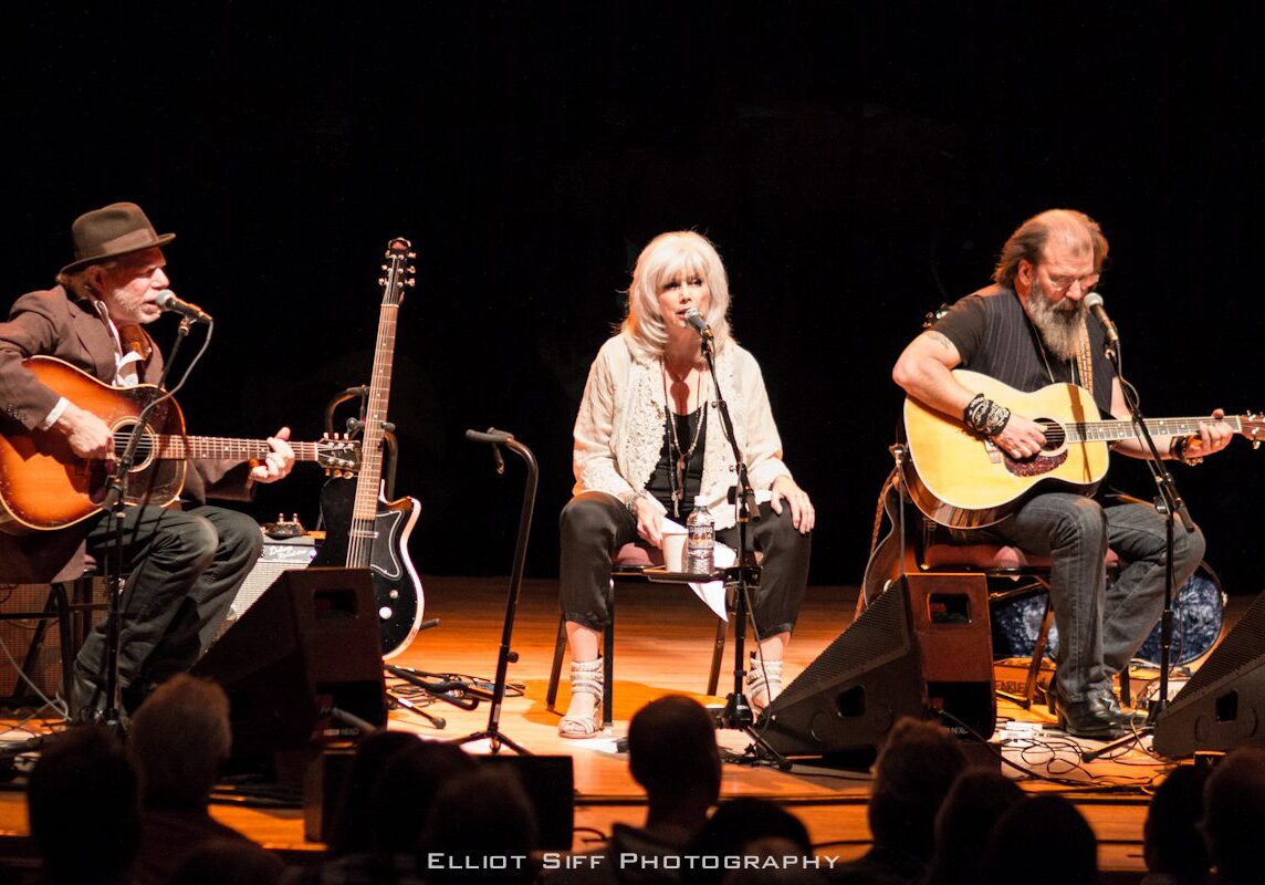Three musicians performing on stage with guitars.