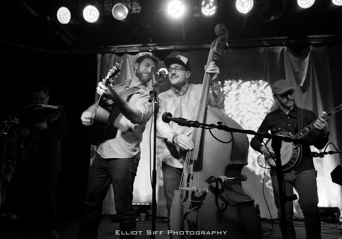 Band performing on stage with string instruments.