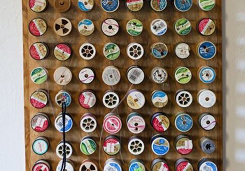 Spools of thread on wooden display rack.