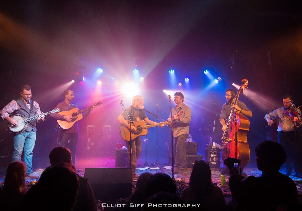 Band performing live on stage with instruments.