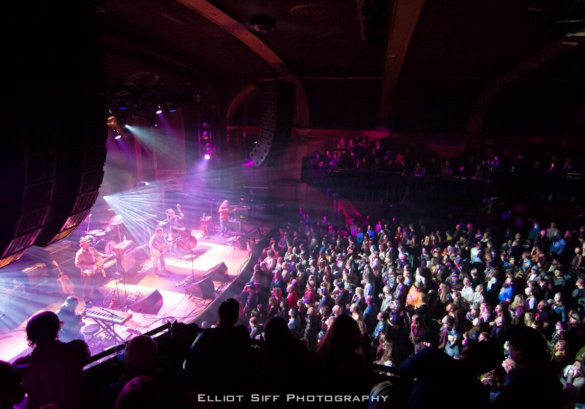 Concert crowd enjoying live band performance.
