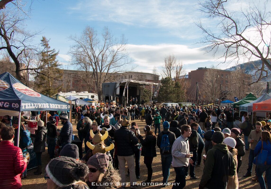 Outdoor festival with crowd and stage setup.