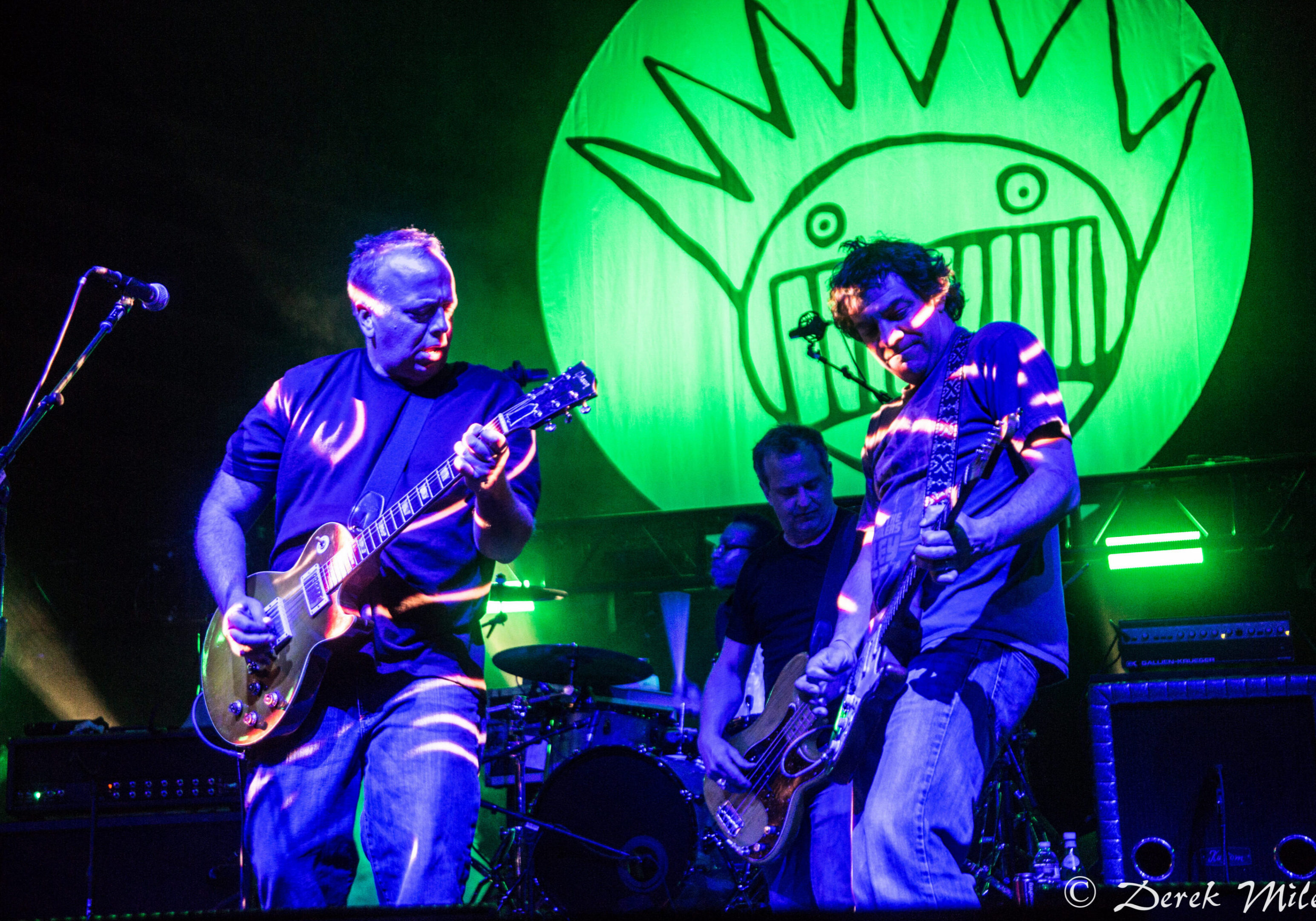 Band performing on stage with green lighting.