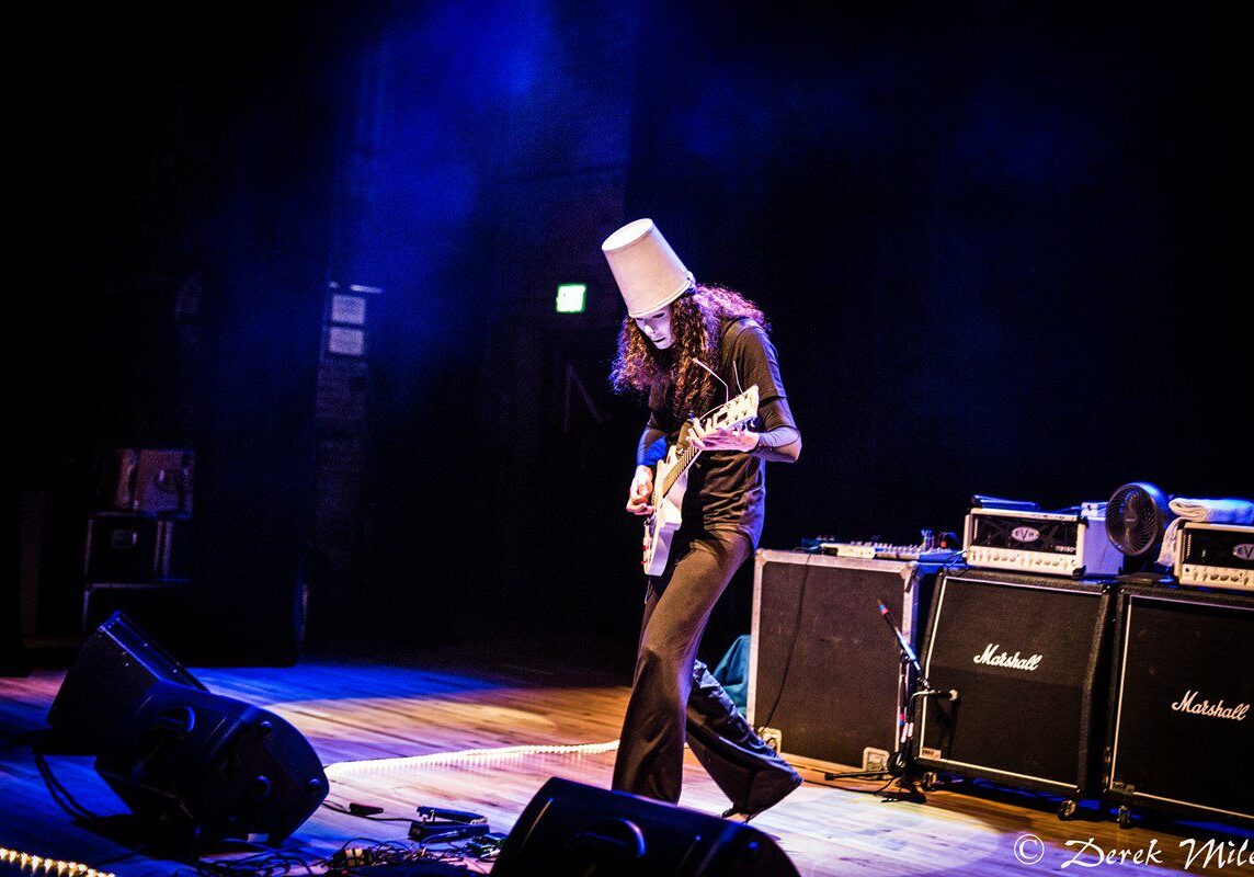 Guitarist performing on stage with amplifiers.