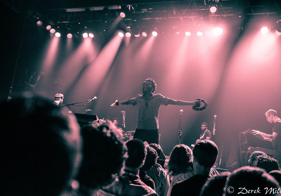 Concert performer with tambourine on stage.