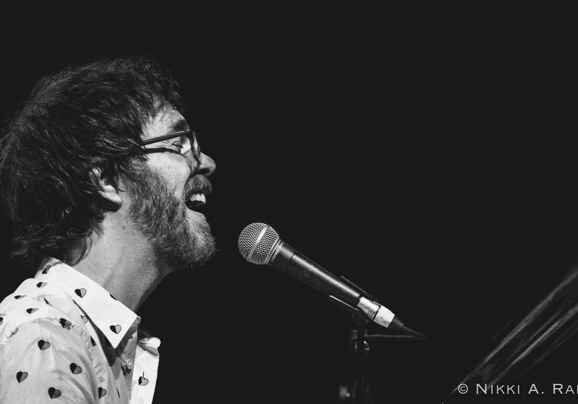 Musician singing passionately into a microphone.