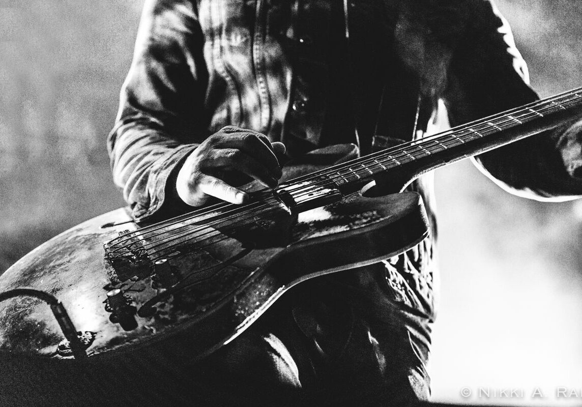 Musician playing electric guitar on stage.