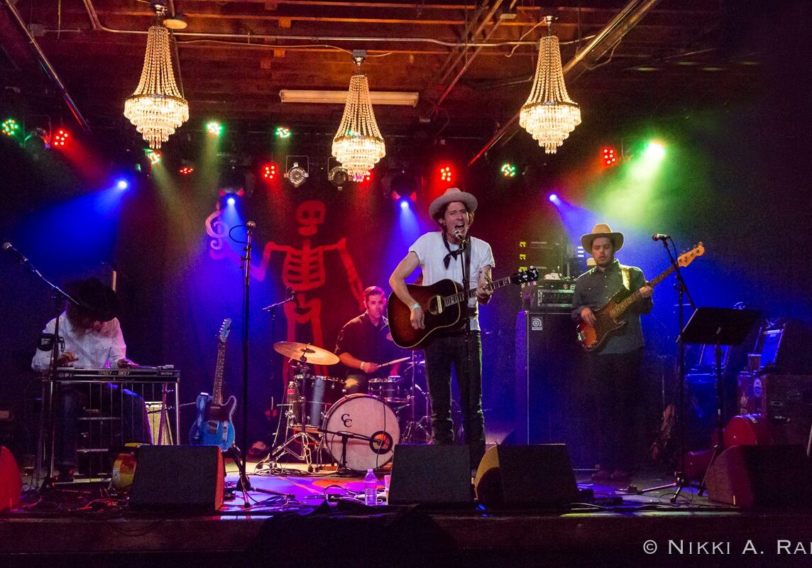 Band performing on stage with colorful lights.