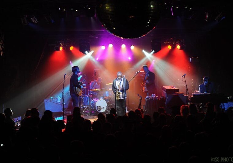 Live band performing on stage with lights.