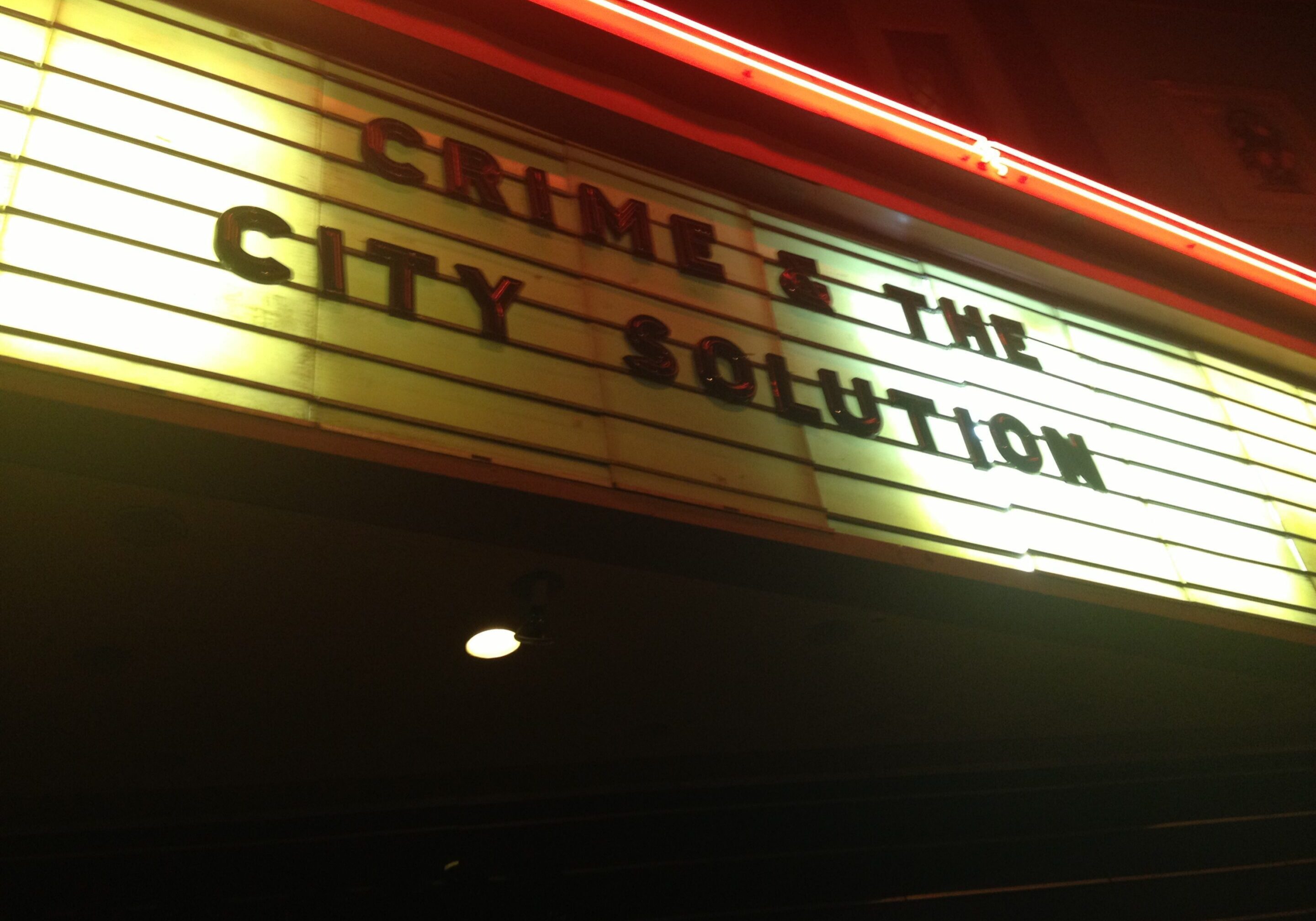 Theater marquee displaying band name at night.