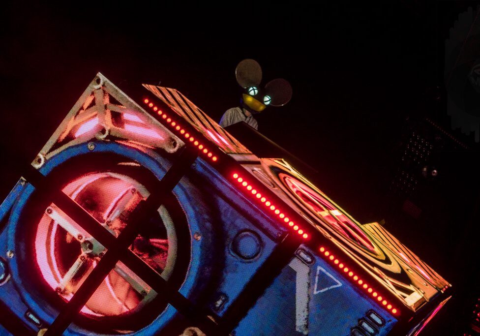 DJ performing with illuminated cube stage setup.