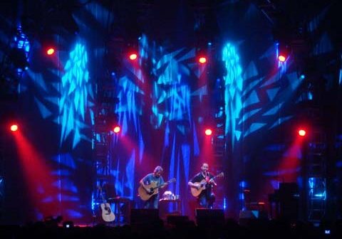 Musicians performing on stage with colorful lights.