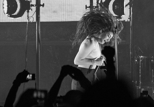 Singer performing energetically on stage, grayscale photo.