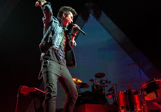 Singer performing energetically on stage with microphone.