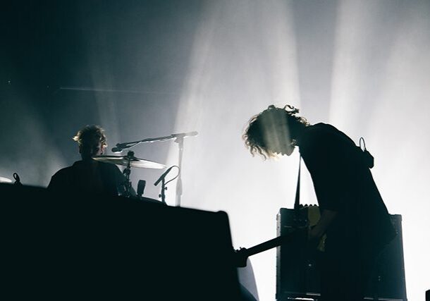 Silhouetted musicians performing on stage with lights.