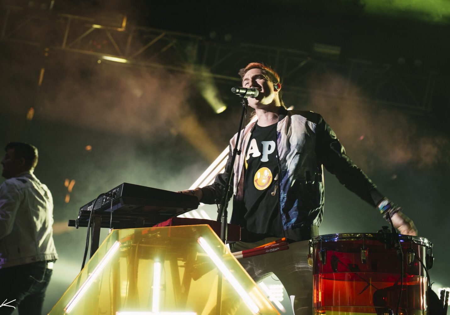 Musician performing energetically on stage with lights.