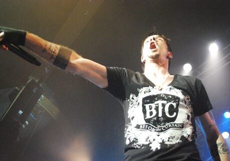 Singer performing energetically on stage with microphone.